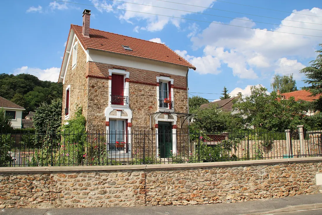 Pavillon en meulière à Palaiseau : chaînes de brique et clôture assortie.